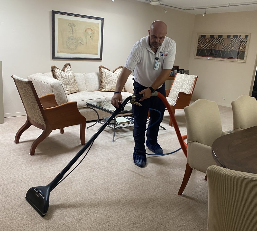Professional cleaner using specialized equipment to deep clean carpet in a Barrington Hills living room with modern furnishings and a cozy atmosphere.