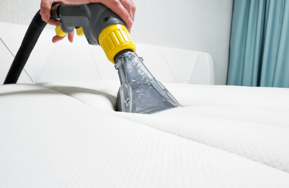 Hand using a specialized cleaning tool on a white mattress, demonstrating professional mattress cleaning services offered by Wiz Team, Inc. in Kildeer, IL.