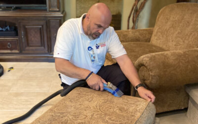 Professional cleaner using upholstery cleaning equipment on a patterned couch, demonstrating effective maintenance techniques for home upholstery.