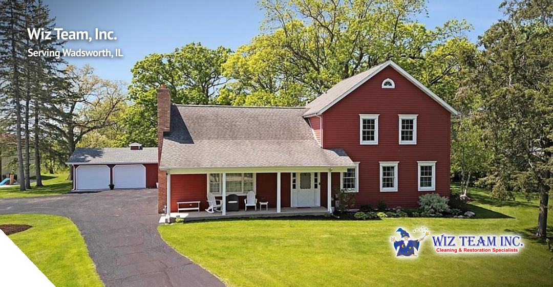 Wiz Team, Inc. logo on a red two-story house in Wadsworth, IL, surrounded by greenery and a well-maintained lawn, showcasing the tranquil rural atmosphere of the village.