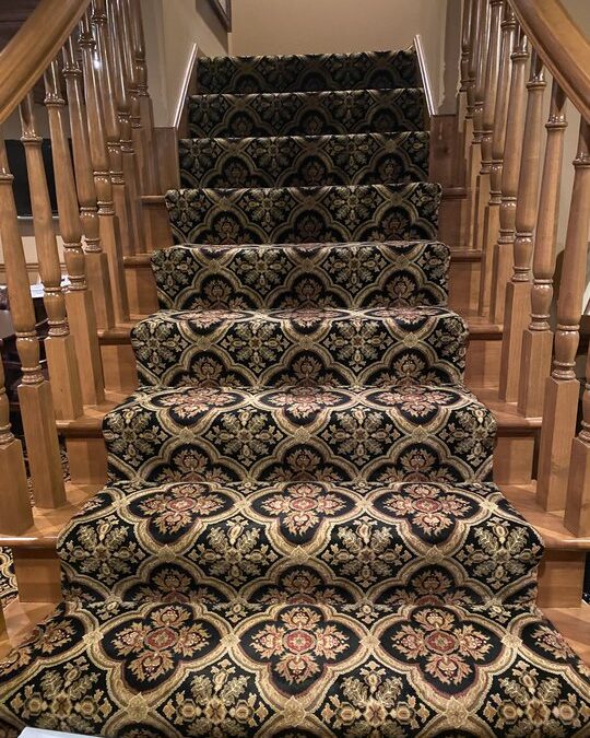 Staircase covered in ornate black and gold patterned carpet, showcasing the elegance of textile conservation in Lake Forest homes.