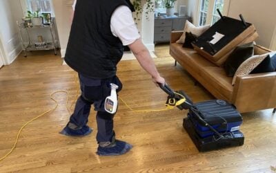 Professional cleaner using a hardwood floor cleaning machine in a well-lit living room, showcasing effective floor maintenance techniques relevant to Wiz Team Inc.'s cleaning services.