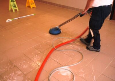 Professional tile and grout cleaning in progress, showcasing steam cleaning equipment on tiled floor, with caution signs in the background.