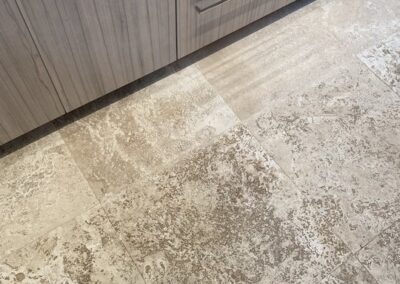 Tile floor with visible dirt and stains, adjacent to a wooden cabinet, emphasizing the need for professional tile and grout cleaning services by Wiz Team, Inc.