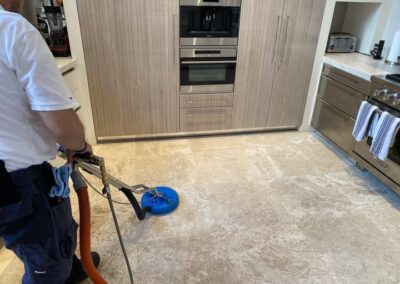 Professional technician using advanced steam cleaning equipment on tile floor, showcasing tile and grout cleaning service by Wiz Team, Inc. in a modern kitchen setting.