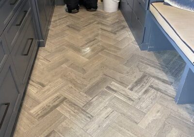 Tile floor in herringbone pattern, showcasing clean and polished surface, highlighting professional tile and grout cleaning services by Wiz Team, Inc.