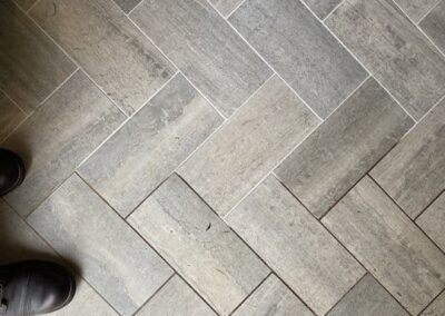 Tile floor in herringbone pattern with visible foot and professional cleaning potential, relevant to Wiz Team, Inc.'s tile and grout cleaning services.