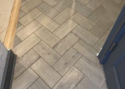 Herringbone-patterned tile flooring showcasing clean, restored surfaces, highlighting professional tile and grout cleaning services by Wiz Team, Inc.
