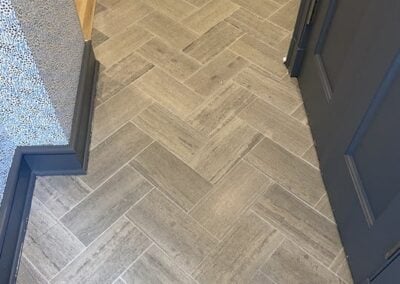Herringbone-patterned gray tile flooring in a modern interior setting, highlighting the pristine condition ideal for professional tile and grout cleaning services by Wiz Team, Inc.