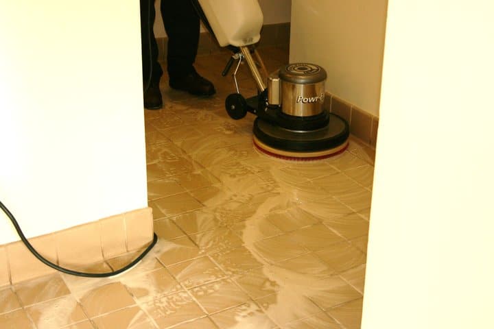Professional tile and grout cleaning in action, showcasing a cleaning machine on tiled floor with cleaning solution, emphasizing hygiene and maintenance for home surfaces.