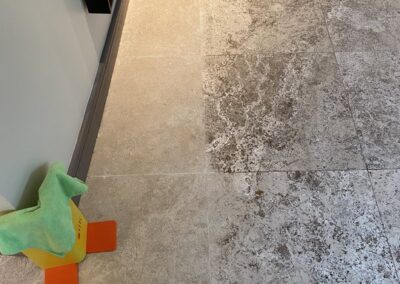 Tile flooring with visible stains and a cleaning tool, featuring a green cloth and a yellow and orange cleaning stand, representing professional tile and grout cleaning services by Wiz Team, Inc.