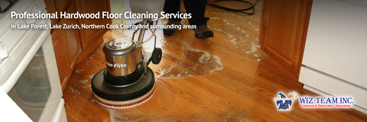 Professional hardwood floor cleaning service in action, featuring a cylindrical auto scrubber on wooden floors with cleaning solution, highlighting eco-friendly techniques used by Wiz Team, Inc. in Lake Forest and surrounding areas.