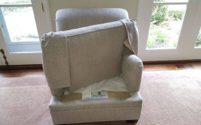 Upholstered armchair with loose fabric cover, showcasing upholstery cleaning process, set in a well-lit room with large windows, emphasizing home maintenance in Lake Forest, IL.