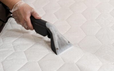 Hand using a professional cleaning tool on a white mattress, highlighting the importance of mattress cleaning for a healthy home environment in Lake Forest, IL.