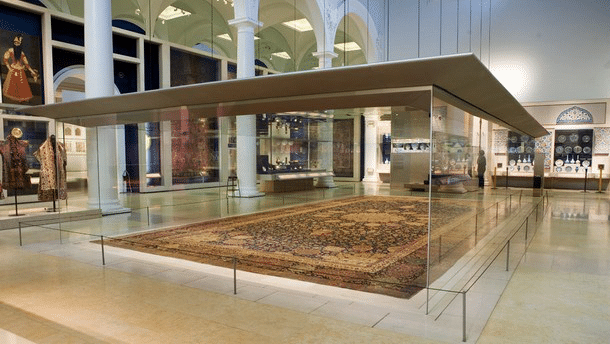 Persian carpet displayed in a museum exhibit, showcasing intricate designs and historical significance, relevant to carpet cleaning and restoration discussions.
