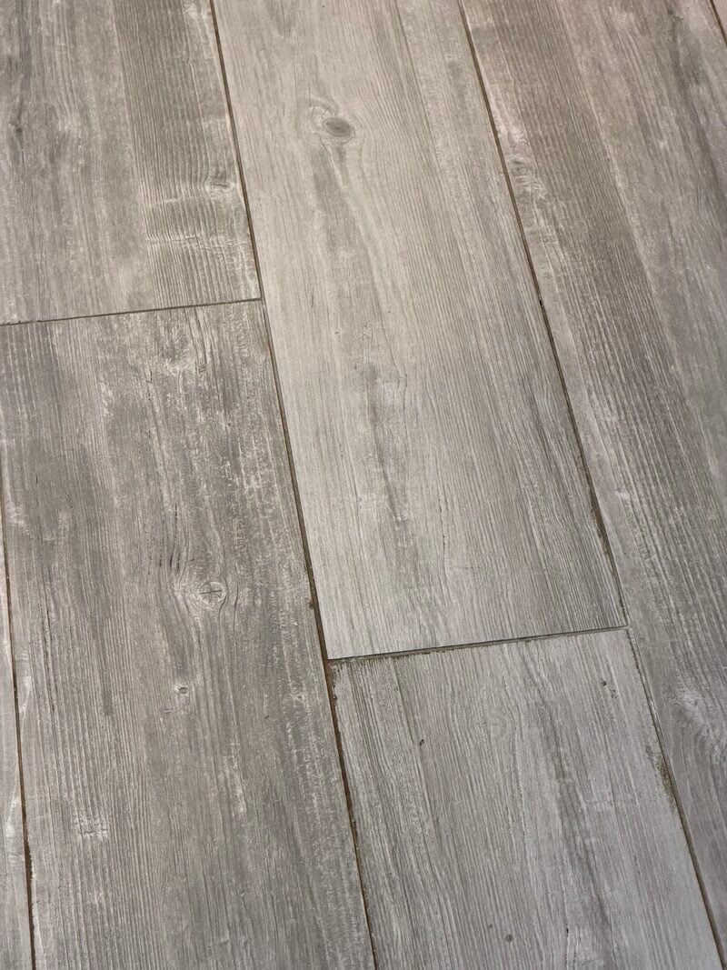 Tile flooring with a weathered wood appearance, showcasing dull and uneven surfaces, indicative of wear and improper maintenance, relevant to professional tile and grout cleaning services in Northbrook, IL.