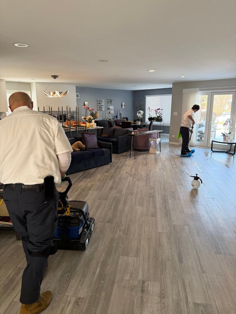 Professional cleaners using equipment to restore tile floors in a modern living room, showcasing the cleaning process for effective tile and grout restoration.