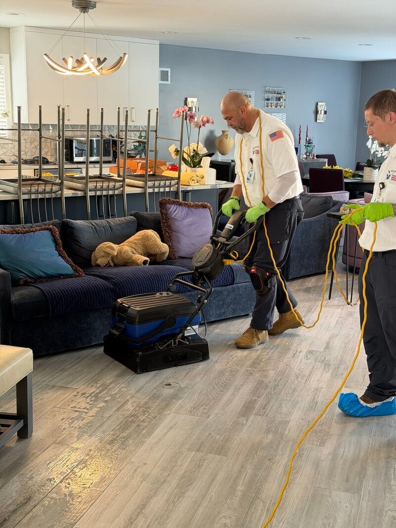 Professional cleaners using equipment for tile and grout restoration in a home setting, showcasing the cleaning process on dull, discolored floors.
