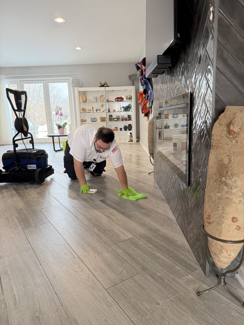 Professional cleaner using green gloves restoring tile floors in a modern living room, showcasing tile and grout cleaning process in Northbrook, IL.